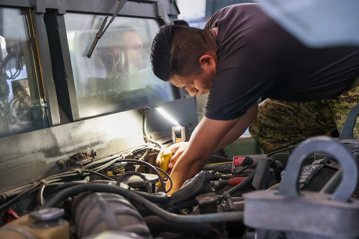 A mechanic working under the bonnet of a car