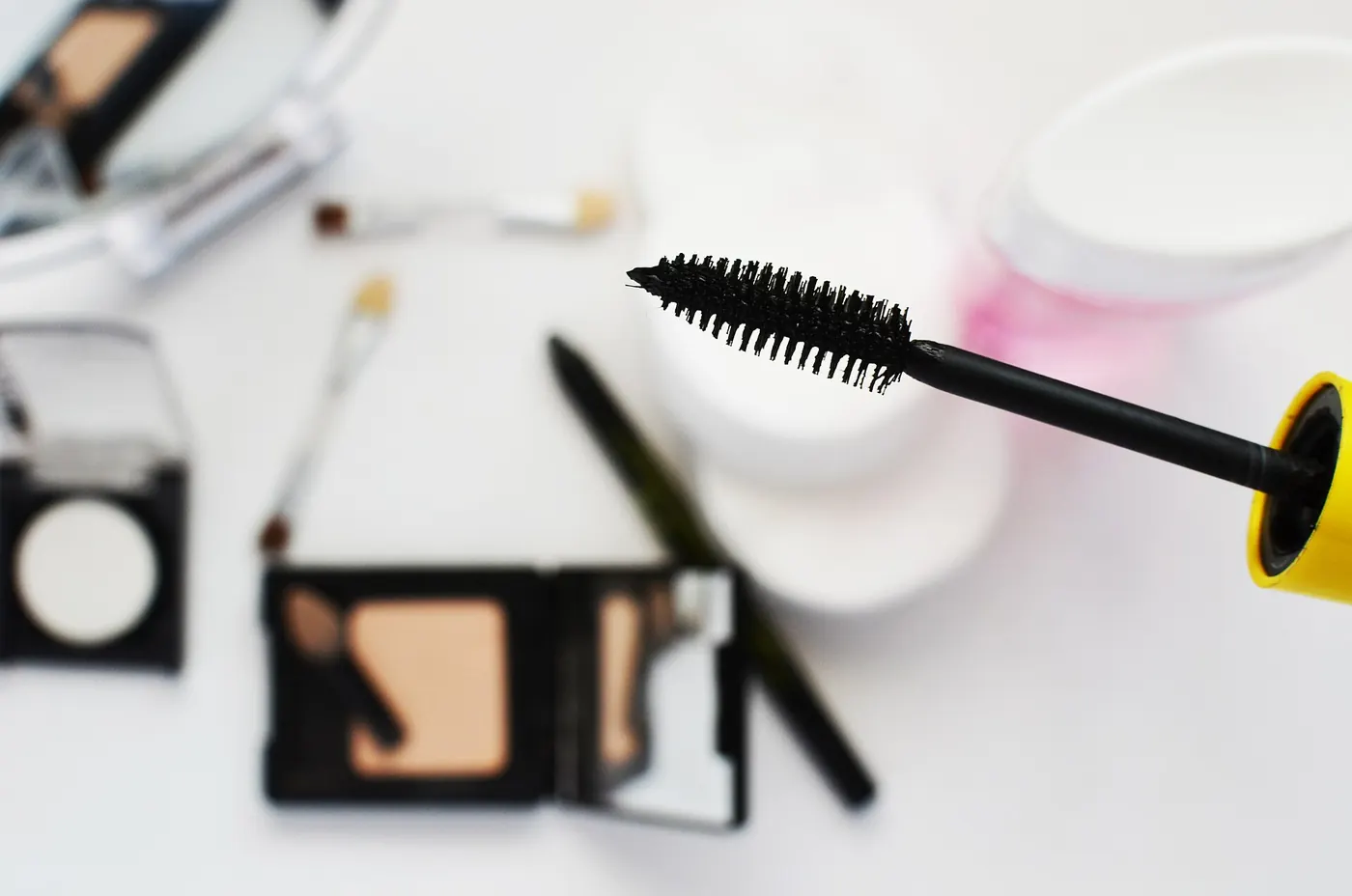 Makeup flat lay with mascara, powder and brushes