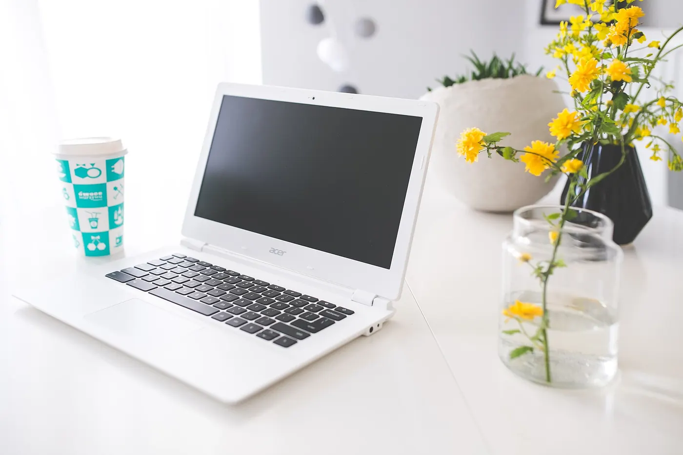 A laptop on a bright desk with flowers