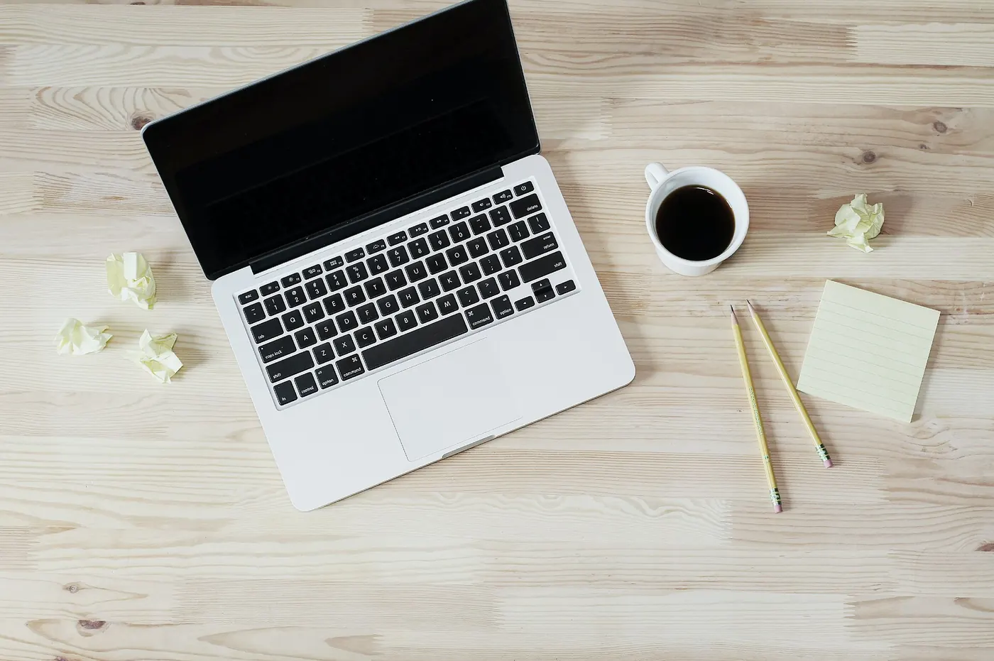 A laptop, coffee and notes on a wooden desk