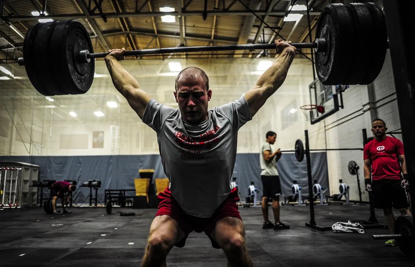 An athlete lifting a barbell overhead in a gym