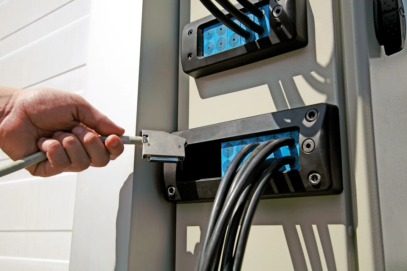 An electrician's hand plugging in an electric vehicle charger