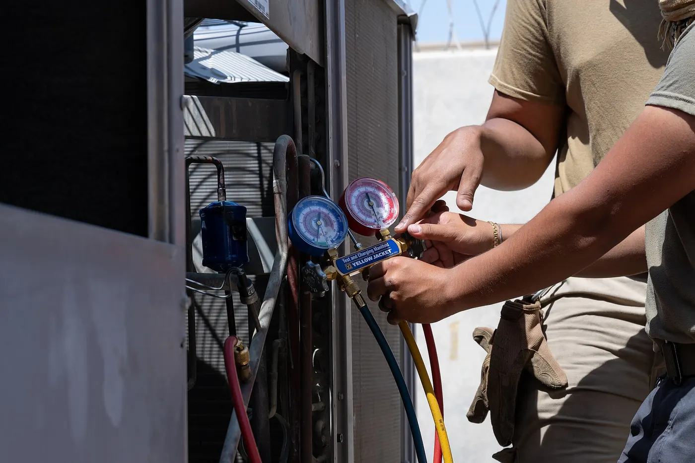 A technician checking an air conditioning unit with pressure gauges