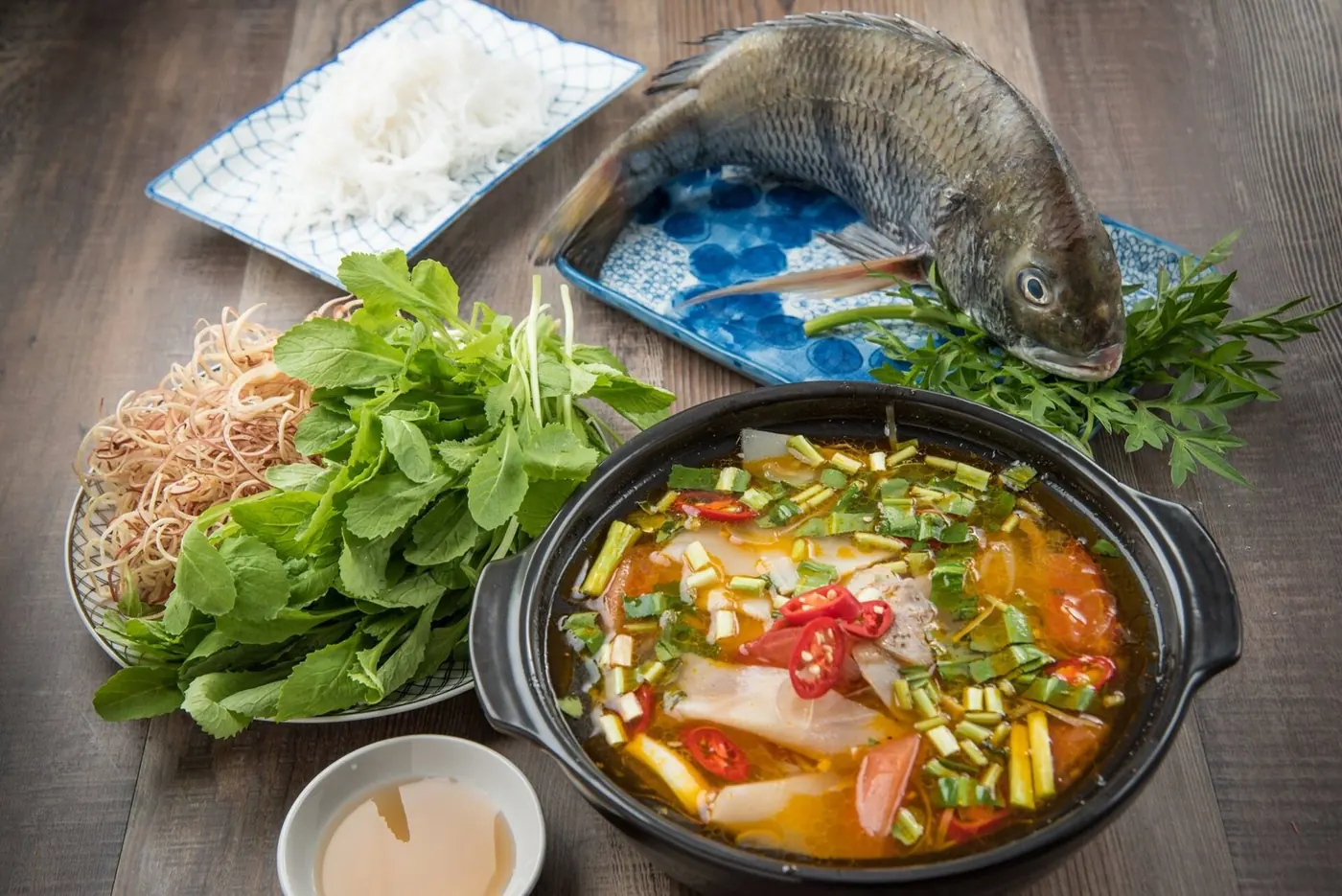 A bowl of soup with fresh herbs and sides