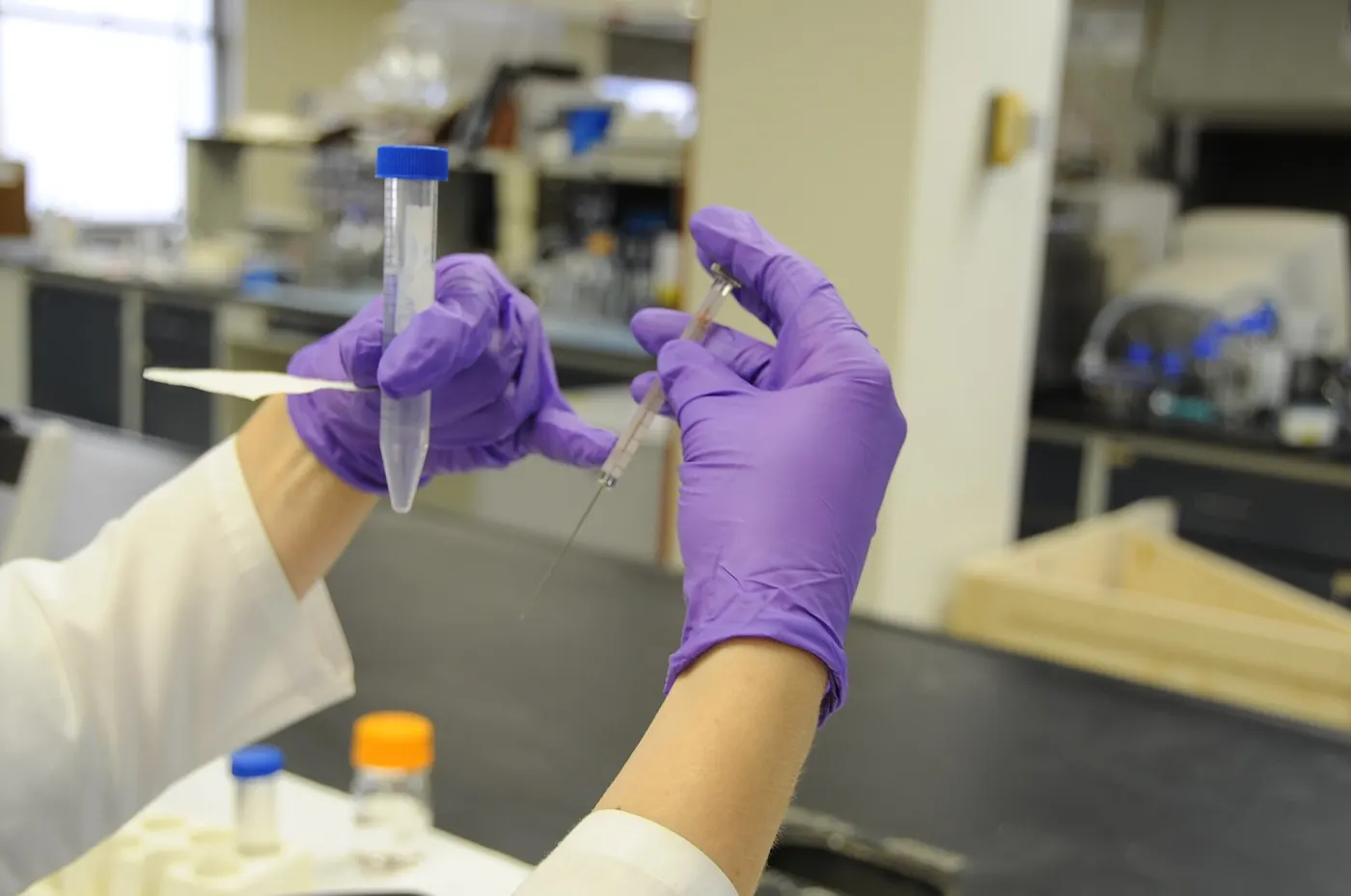 Gloved hands preparing a syringe from a vial