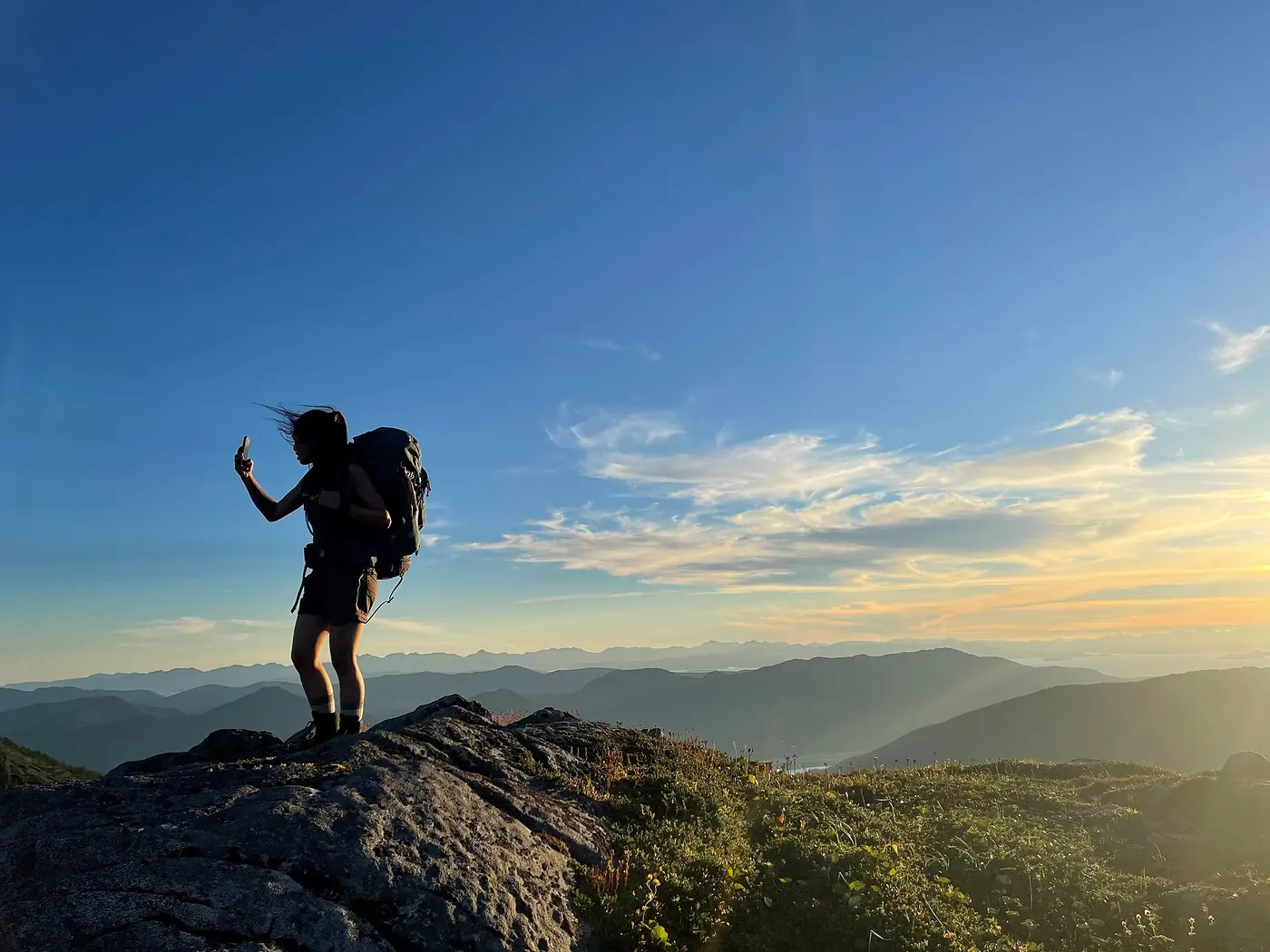 A hiker on a summit at sunset