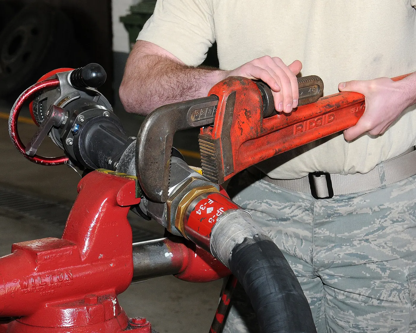 A pipe wrench gripping a pipe fitting