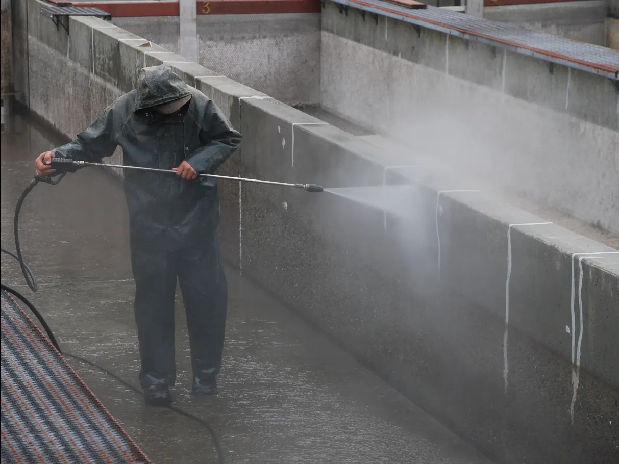 A worker pressure washing a concrete surface