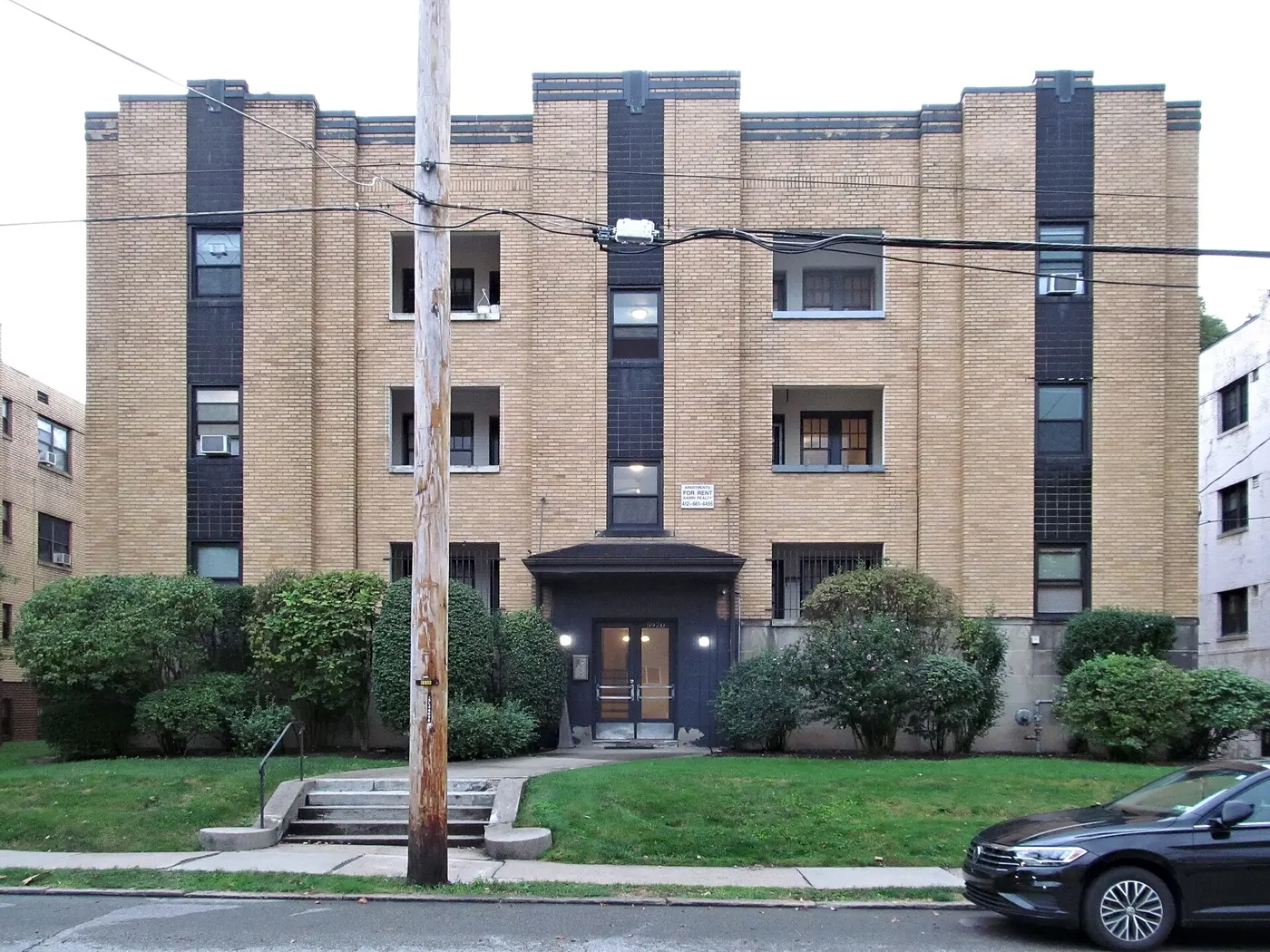 A low-rise apartment building with a front garden