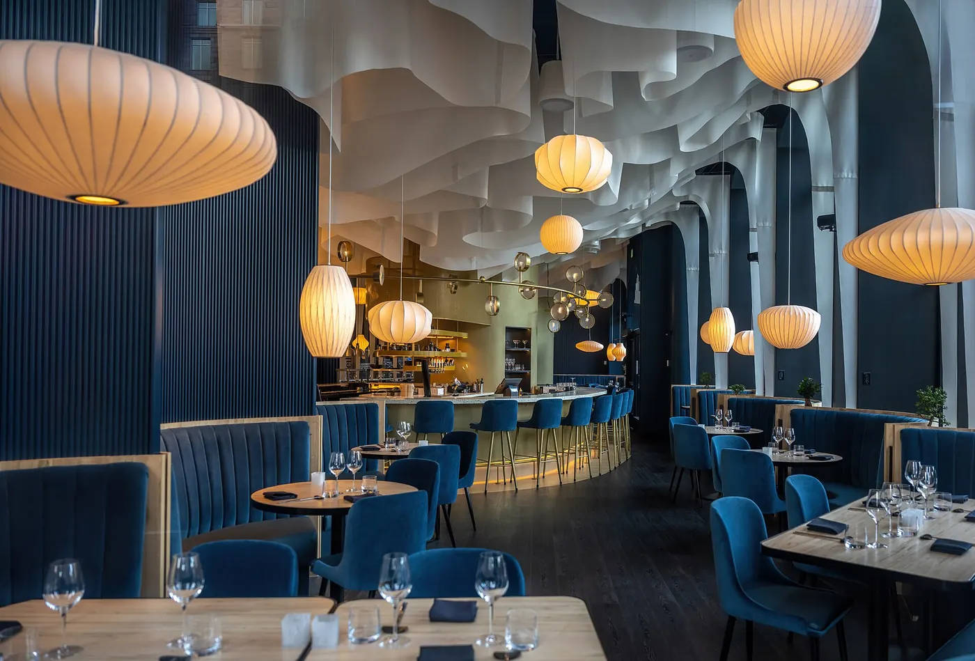A restaurant dining room with pendant lights and blue booths