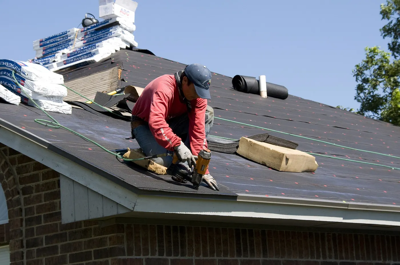 A roofer laying shingles on a house roof