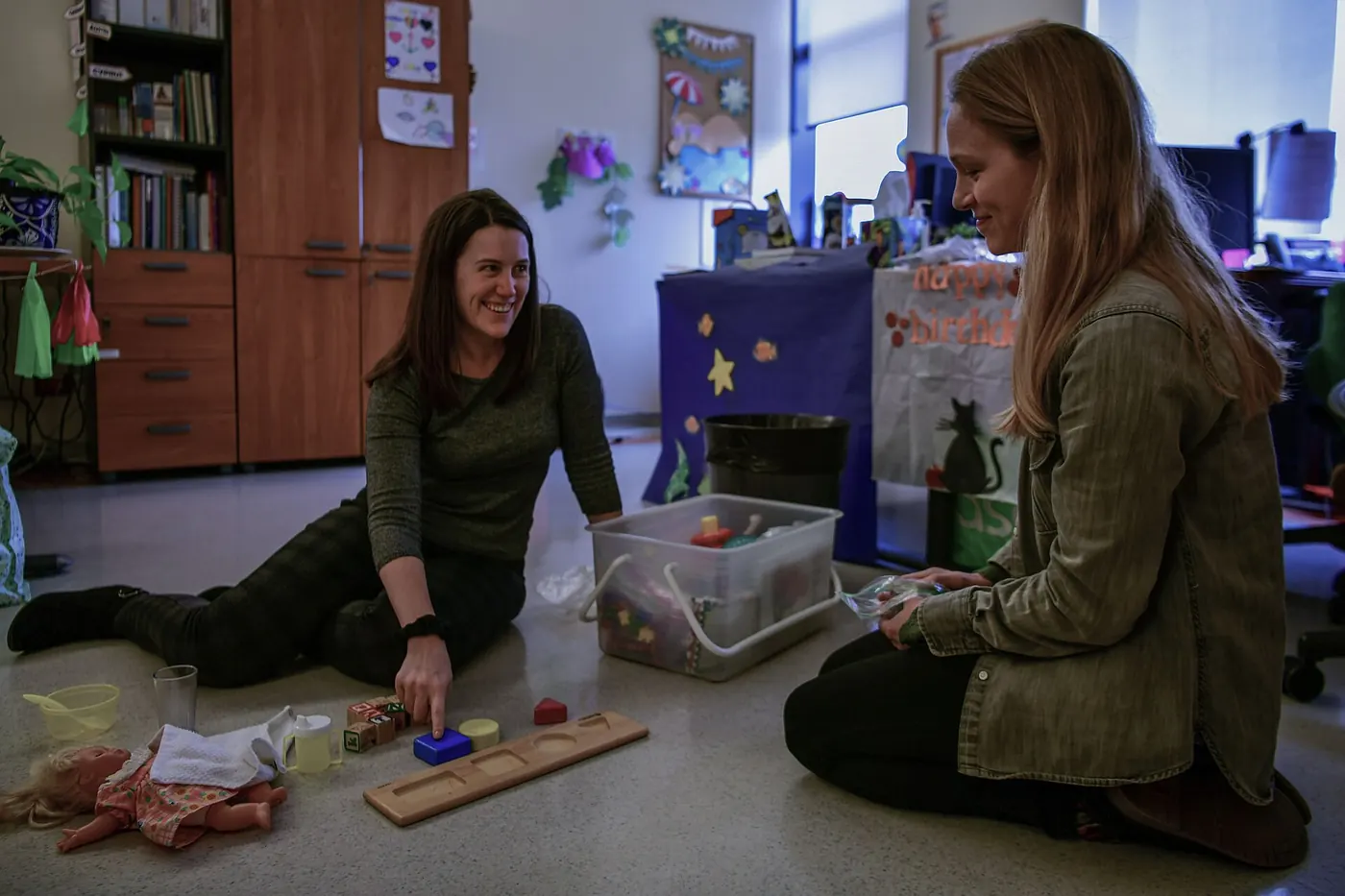 A therapist playing a learning game with a child on the floor