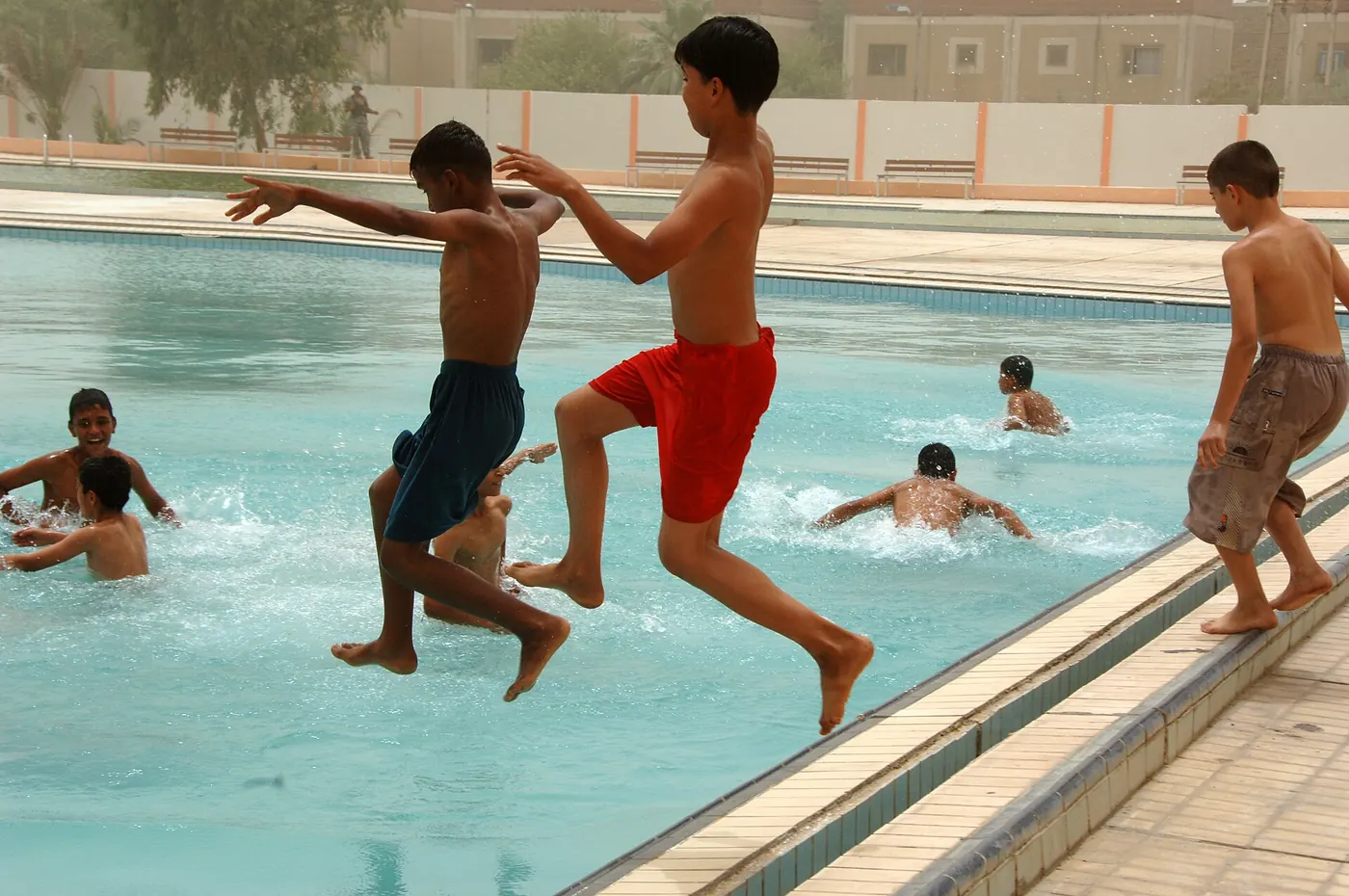 Children jumping into an outdoor swimming pool